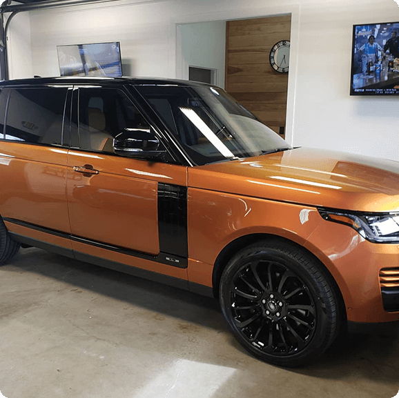 An orange land rover parked in a garage.